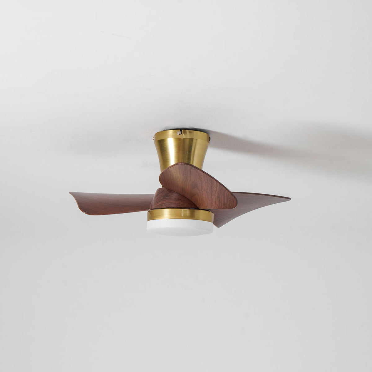 The Clérachic gold ceiling fan in motion, with its blades soft at the edges and the white light diffuser unlit at the base.