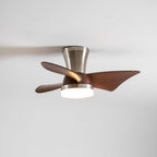 A Clérachic nickel ceiling fan with a warm light on, its blades and trumpet-shaped canopy shown from below on a pale ceiling.