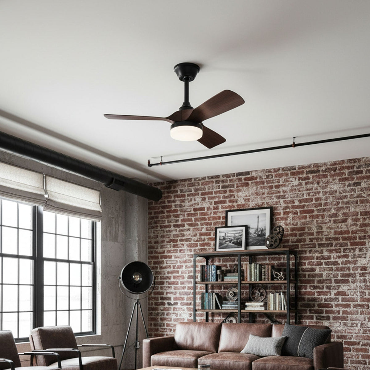 This Clérachic ceiling fan hangs in a loft living room with a red brick wall, black window frames and a leather sofa below.
