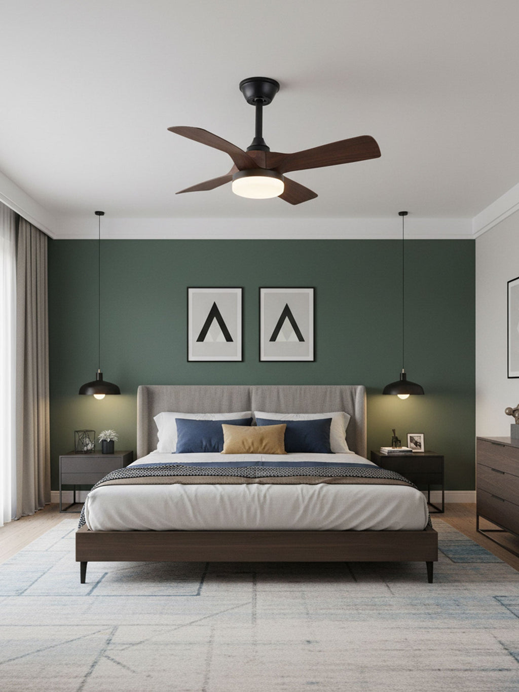 A Clérachic ceiling fan with dark walnut blades and a lit light above a bed with a grey headboard, against a deep green wall.
