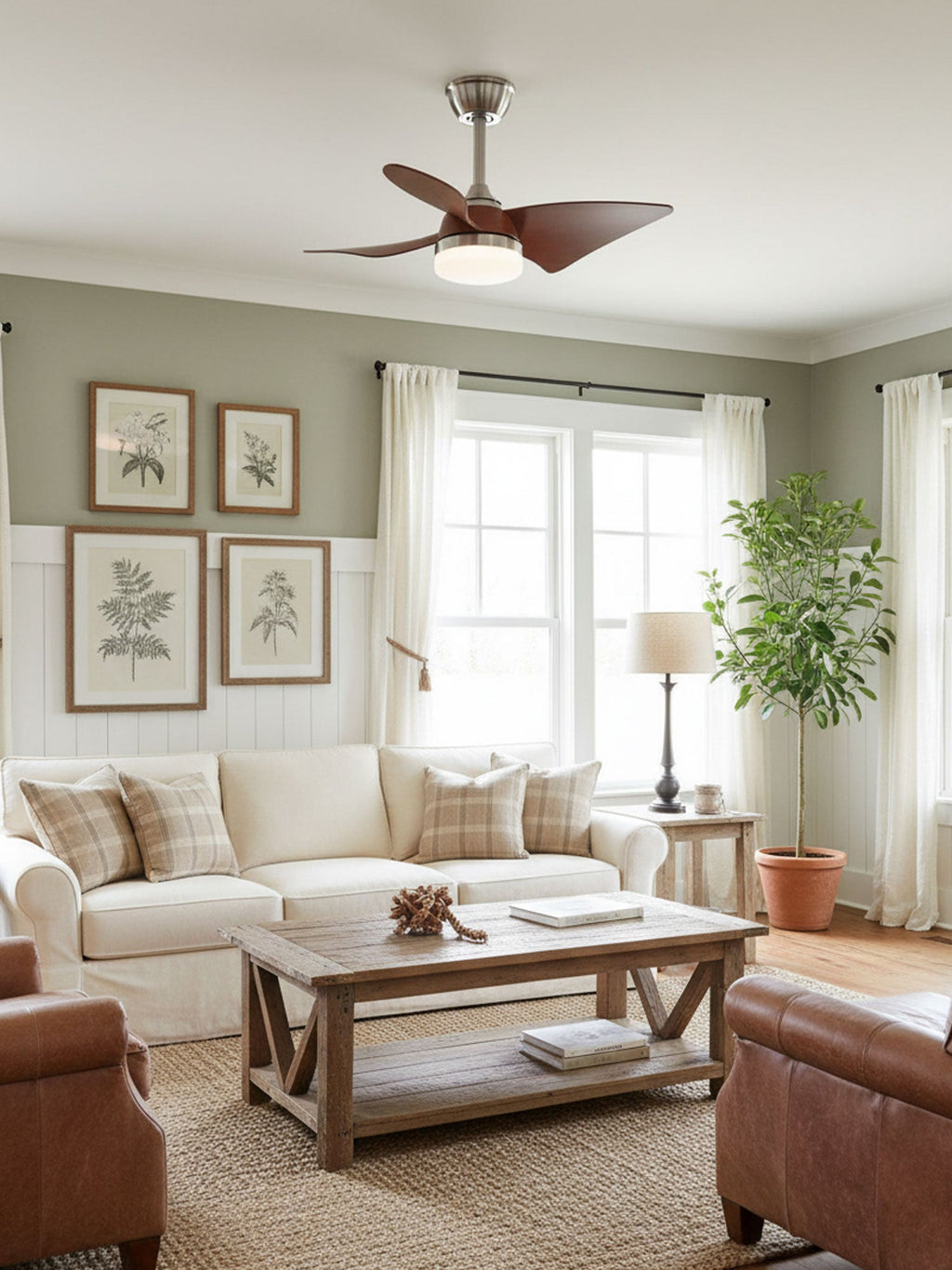 Clérachic ceiling fan with curved walnut blades above a cream sofa, wooden coffee table and leather armchairs in a green-grey room.