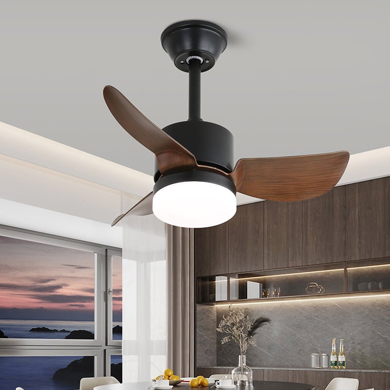 Black motor housing, walnut-effect blades and a lit white light on this Clérachic ceiling fan, above a dining area at dusk.