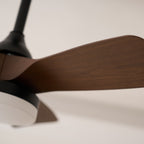 Close view of the wood-grain finish on a single fan blade and the black stem above, on this Clérachic ceiling fan.