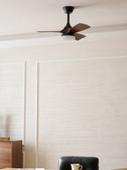 Close-framed view of this Clérachic fan with a lit light, above a panelled cream wall and a sideboard.