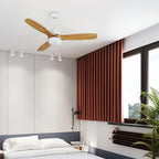 White ceiling fan from Clérachic with wooden blades over a bedroom with a rust-red curtain, spotlights and a large window.