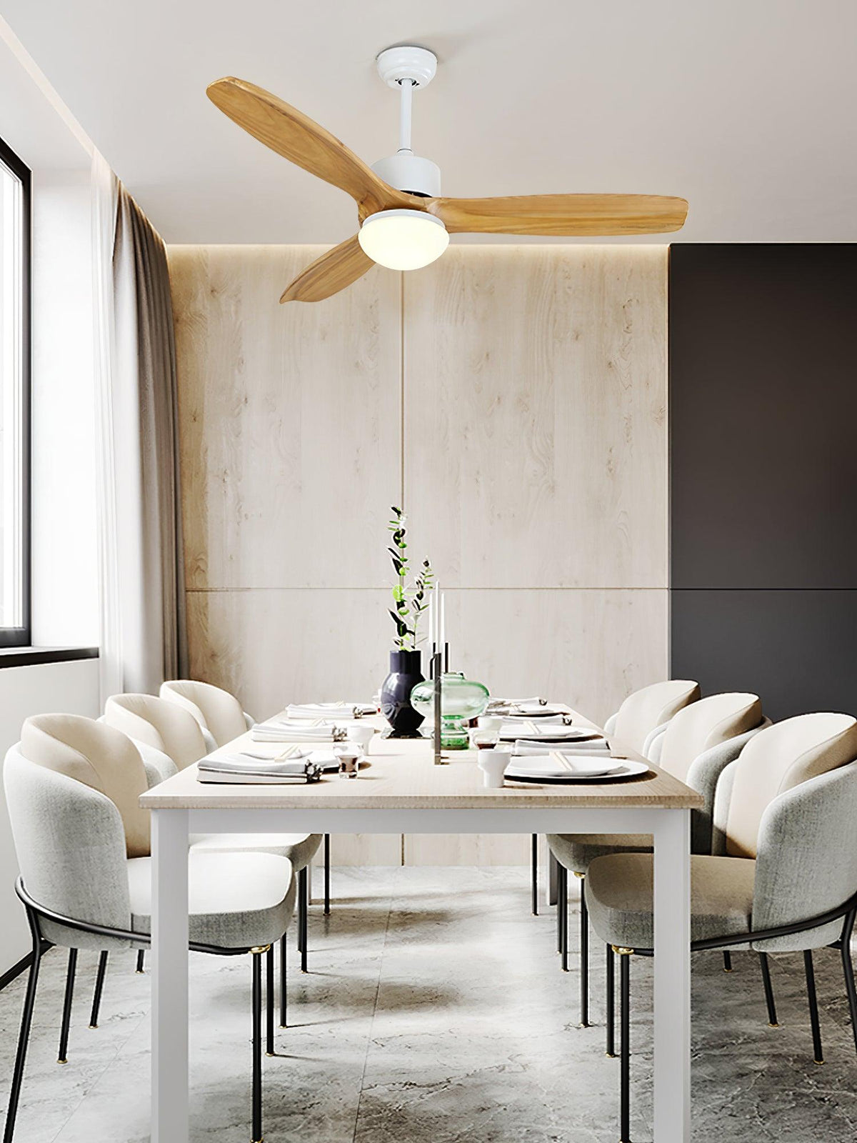 Light wooden-bladed ceiling fan from Clérachic above a dining table with cream chairs, in a room with a pale panelled wall.