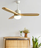 White-bodied ceiling fan from Clérachic with three wooden blades, hung above a light wood sideboard with dried flowers and a plant.
