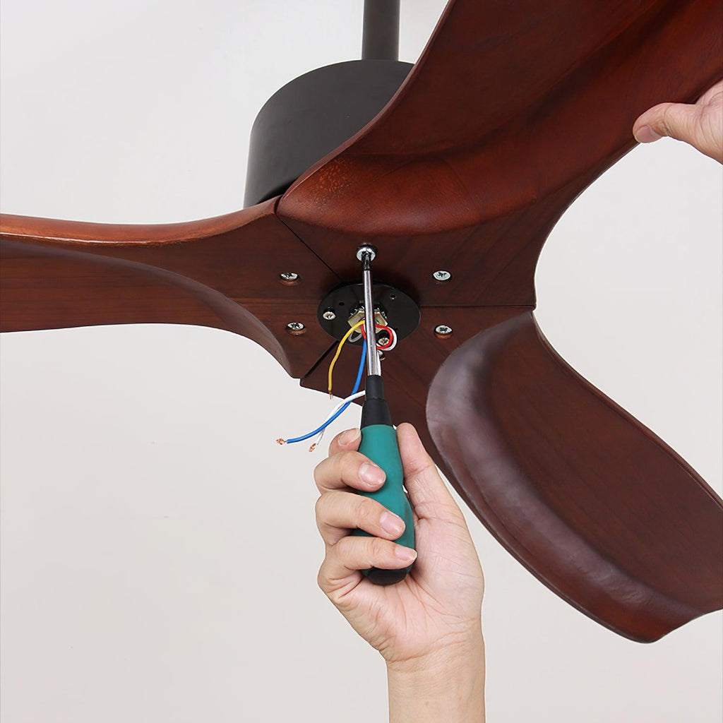 A hand holds a screwdriver at the wiring in the centre of a dark-bladed Clérachic ceiling fan, with coloured wires showing.