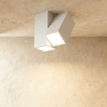 Clérachic white square-section LED ceiling light with two angled lit heads, fixed to a textured plaster ceiling