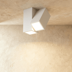 Clérachic white square-section LED ceiling light with two angled lit heads, fixed to a textured plaster ceiling
