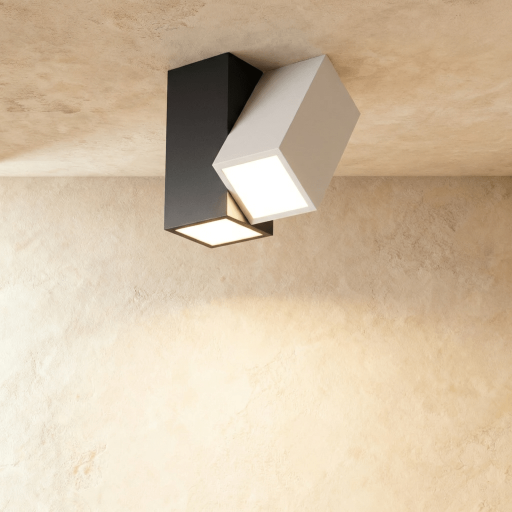Clérachic two-head ceiling light with a black square body and a white angled head, both faces lit warm white