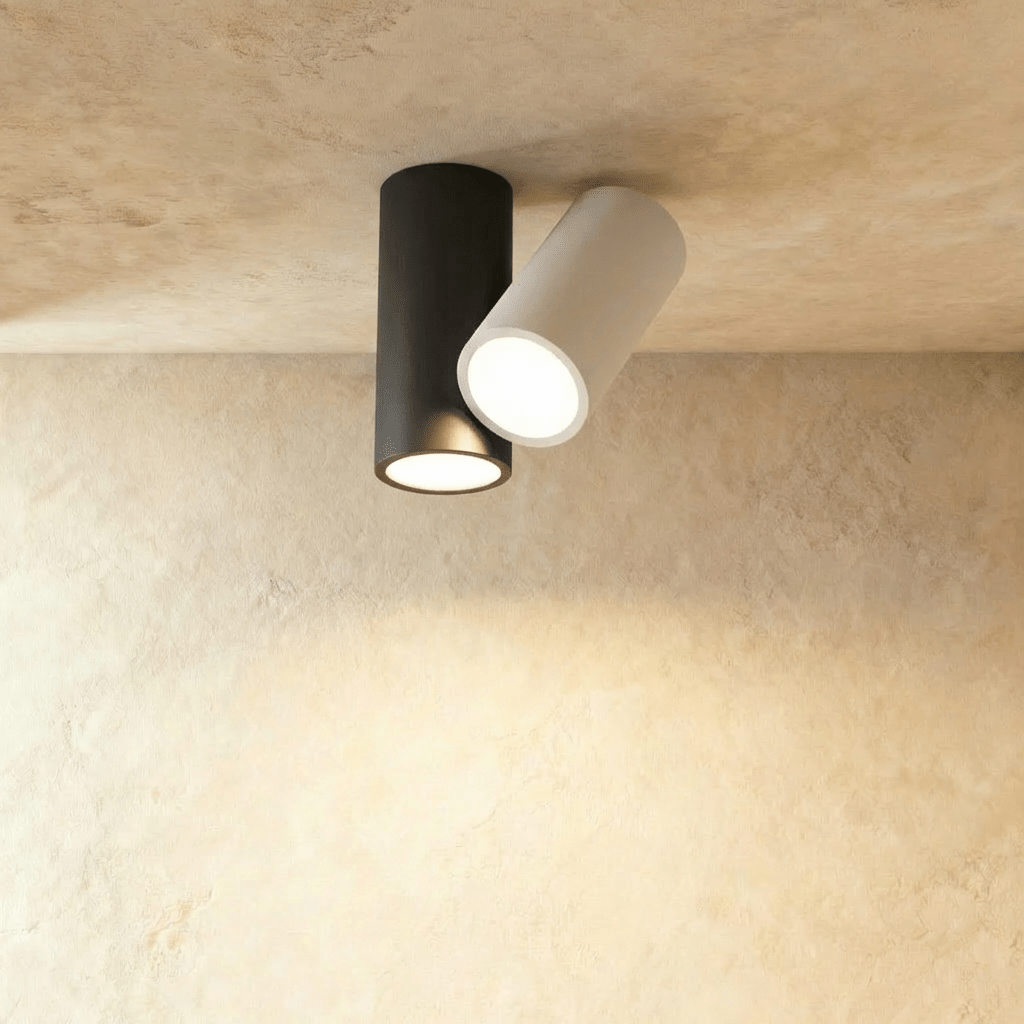 Clérachic ceiling light with a black cylinder and a white tilted cylinder, both lit, on a plaster ceiling