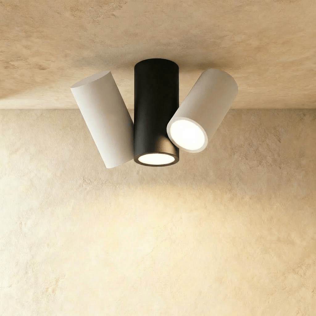 Clérachic three-head cylindrical ceiling light with a black centre and two white tilted heads, all lit