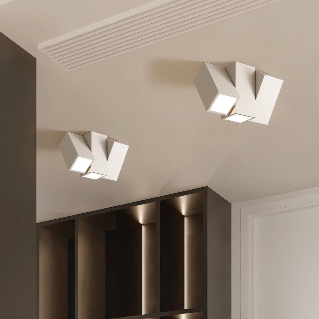 Two Clérachic white square-section ceiling lights with angled lit faces above a dark shelving unit