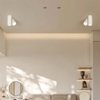 Pair of Clérachic white cylindrical two-head ceiling lights above a living room with shelves and a round mirror