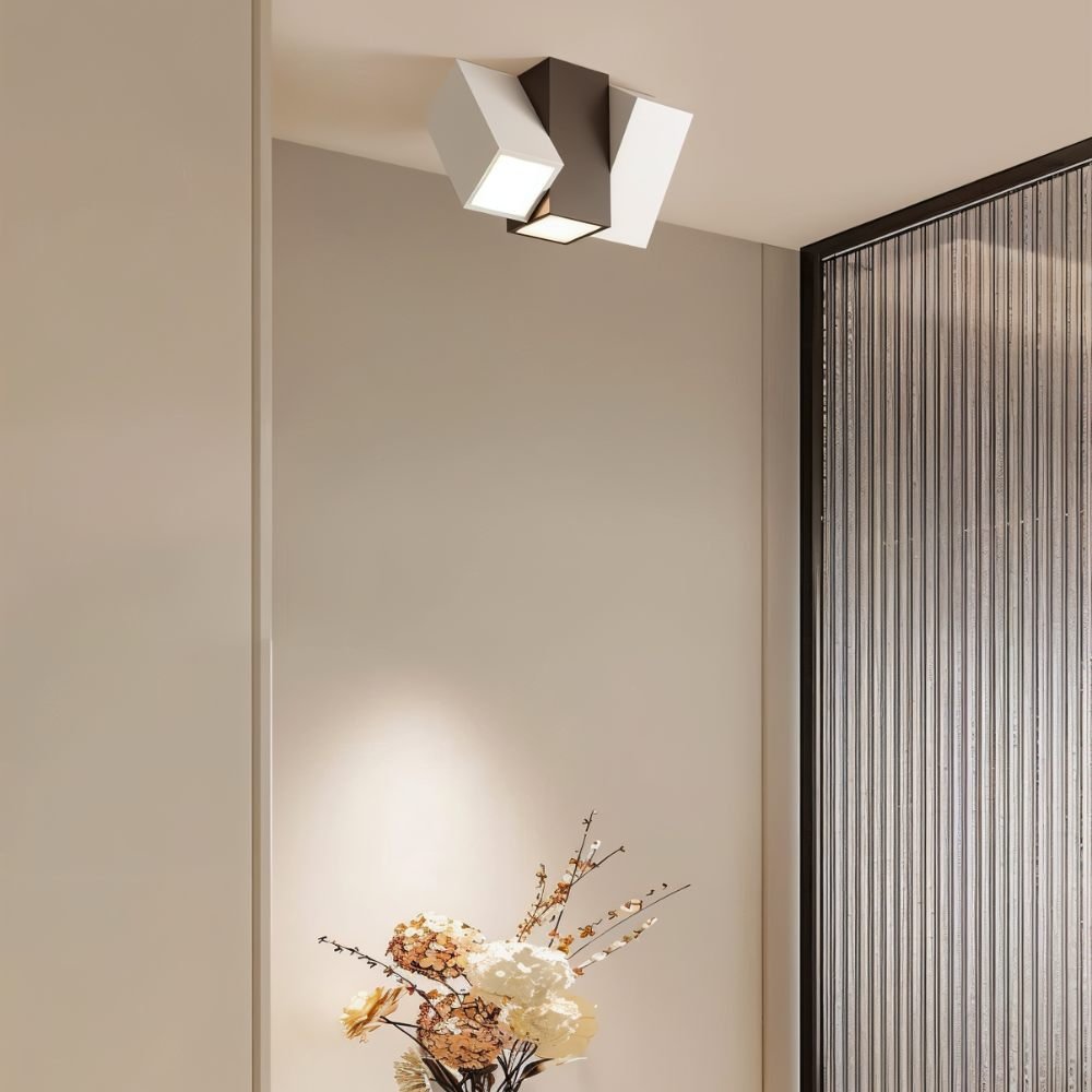 Clérachic square-section ceiling light with a dark centre block and white heads, above a vase of dried flowers