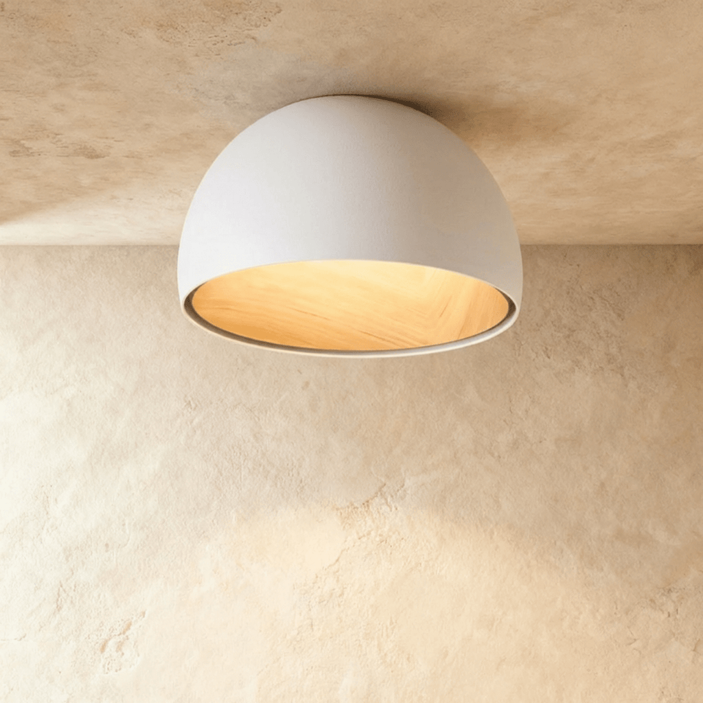Clérachic white domed ceiling light with a glowing wood-grain interior, mounted flush against a limewashed ceiling.