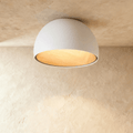Clérachic white domed ceiling light with a glowing wood-grain interior, mounted flush against a limewashed ceiling.