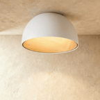 Clérachic larger white domed ceiling light with a wide wood-grain interior, fixed flush to a limewashed ceiling.