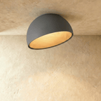 Clérachic grey ceiling light with an angled, slanted-cut dome and a warm wood-grain interior on a limewashed ceiling.