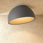 Clérachic larger grey angled-dome ceiling light with a wide, glowing wood-grain interior on a limewashed ceiling.