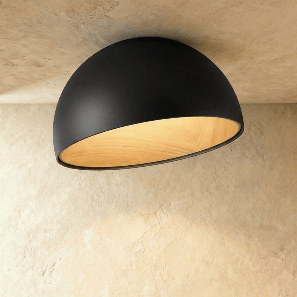 Clérachic larger black angled-dome ceiling light with a wide, glowing wood-grain interior on a limewashed ceiling.