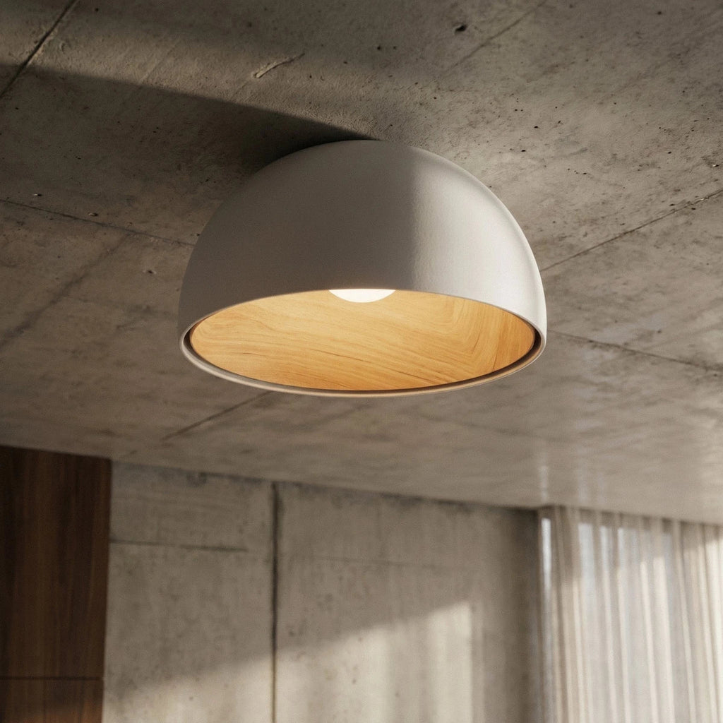 Clérachic white domed ceiling light on a raw concrete ceiling, its wood-grain interior lit, beside sheer curtains and a walnut panel.