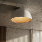 Clérachic white domed ceiling light on a raw concrete ceiling, its wood-grain interior lit, beside sheer curtains and a walnut panel.