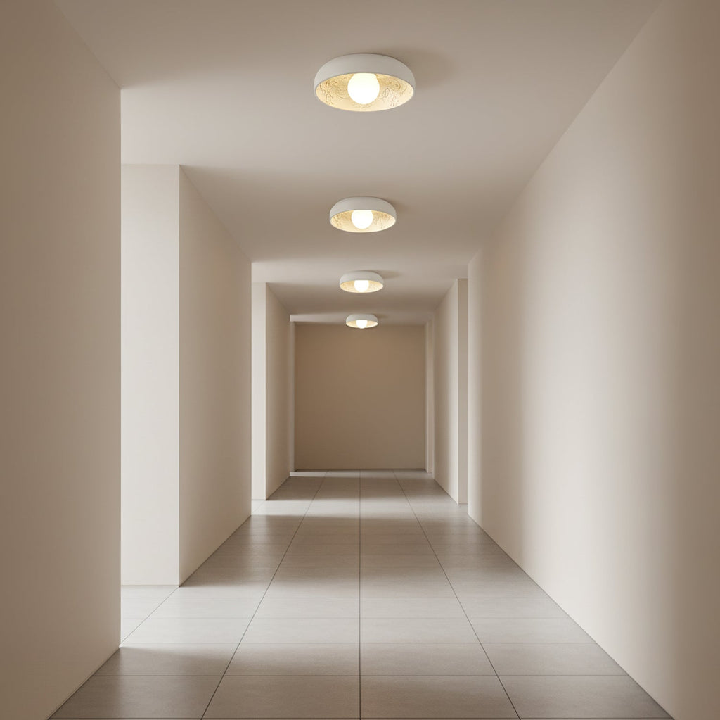 Clérachic flush-mount lights receding along a tiled corridor, each lit with a round globe inside a white bowl.