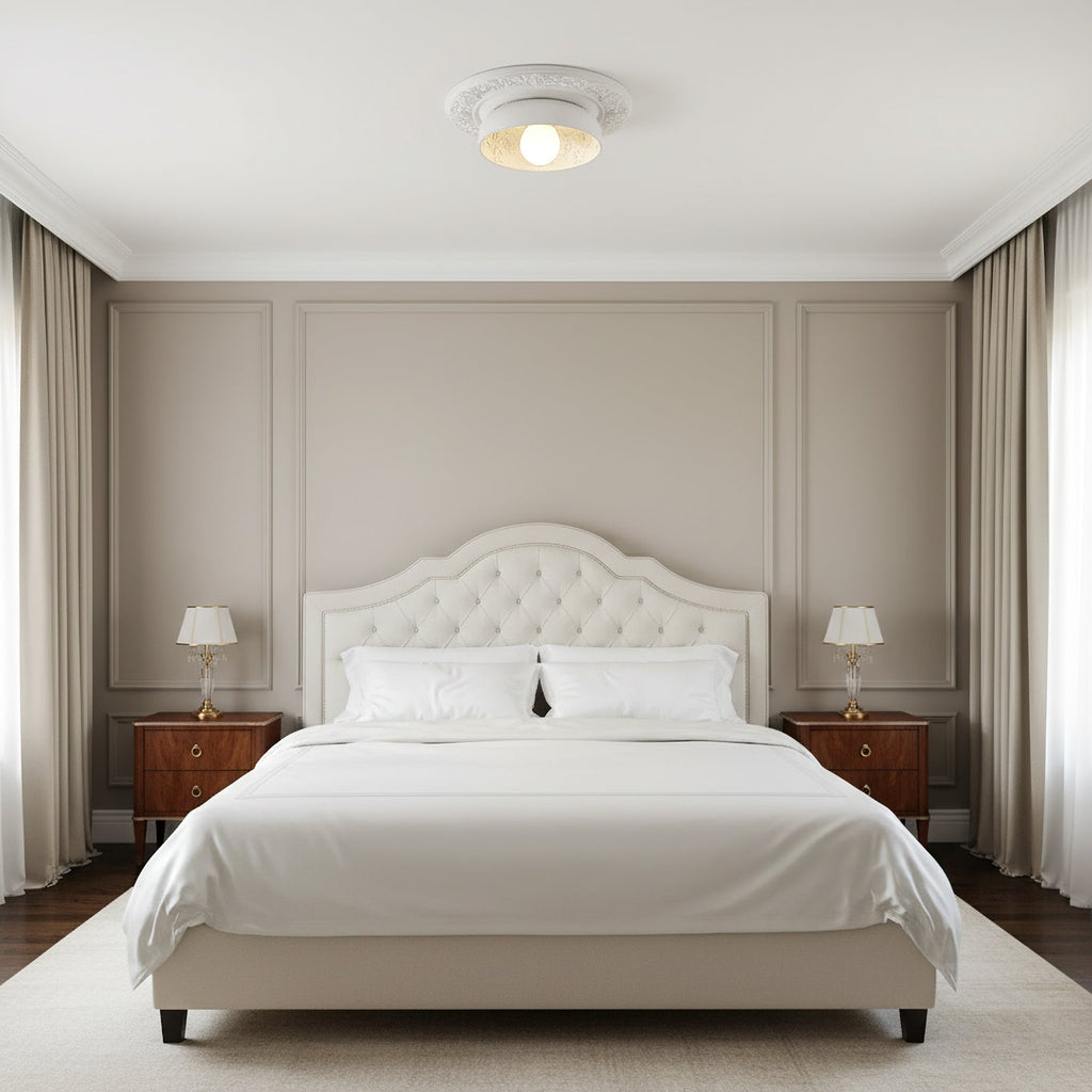 Clérachic white bowl light on a small plaster ceiling rose above a tufted cream bed and two lamps in a panelled bedroom.