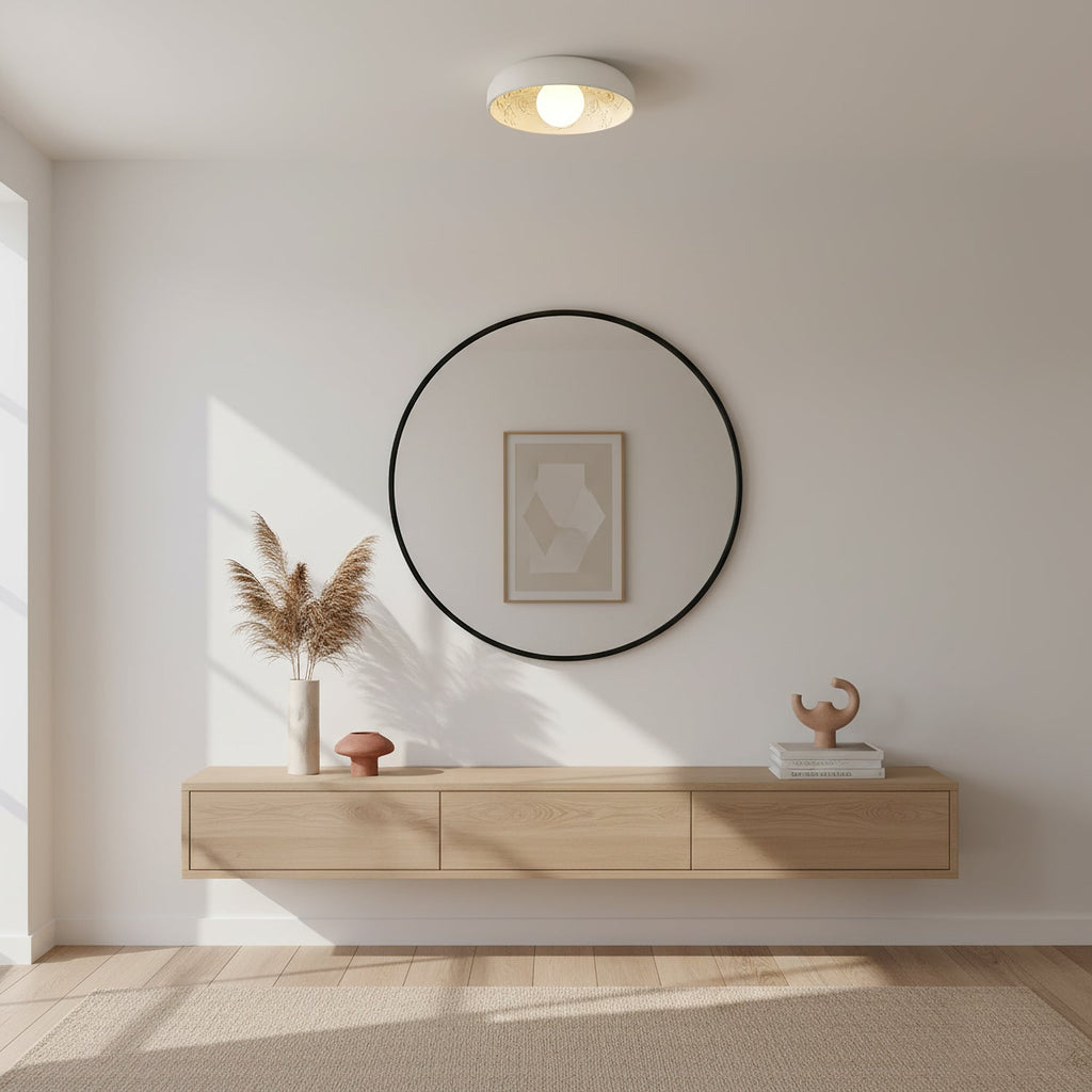 Clérachic carved-resin ceiling light lit above a round black mirror and a pale wood floating shelf in a bright room.