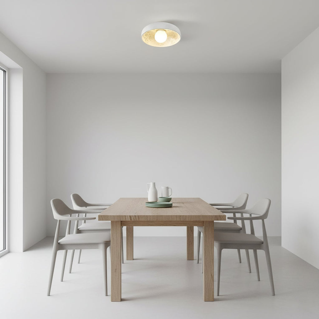 Clérachic white bowl light overhead in a minimal room with a light wood dining table and four grey chairs.