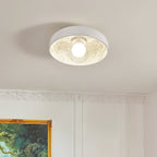 Lit Clérachic bowl light with an engraved leaf pattern inside, on a beige ceiling above panelled white walls and a gilt frame.