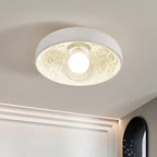Close view of the Clérachic bowl light's carved scrollwork and glowing globe, with a cove light line along the wall behind.
