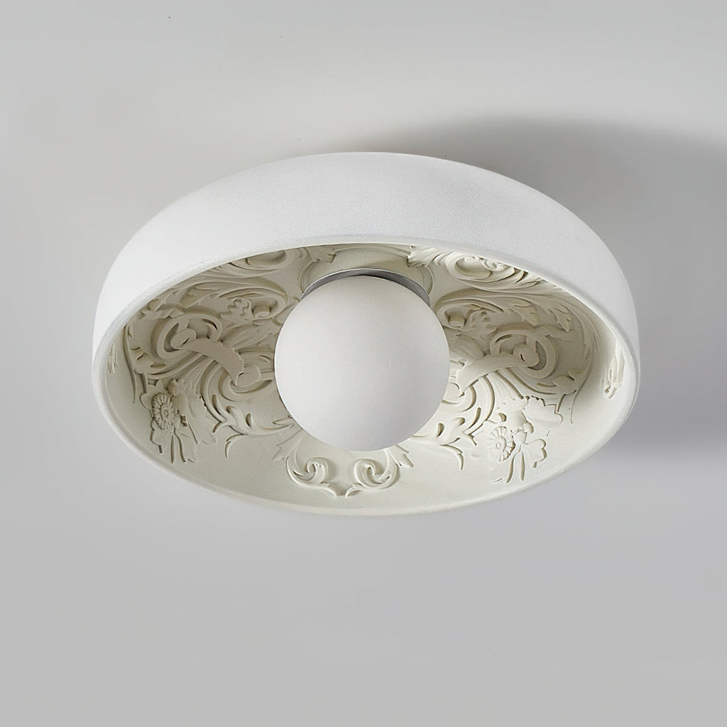 Clérachic flush light seen from below, the clear glass globe unlit, with detailed ornamental relief lining the white bowl.