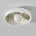Clérachic flush light seen from below, the clear glass globe unlit, with detailed ornamental relief lining the white bowl.