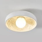Clérachic white flush-mount bowl with a lit frosted globe and a cream, carved interior, on a pale grey ceiling.