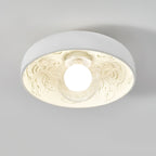 Clérachic bowl light lit with a clear glass globe, its carved interior glowing warm cream against a pale grey ceiling.