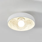 Clérachic white bowl light with its glowing globe, seen from a low angle against a pale grey ceiling.