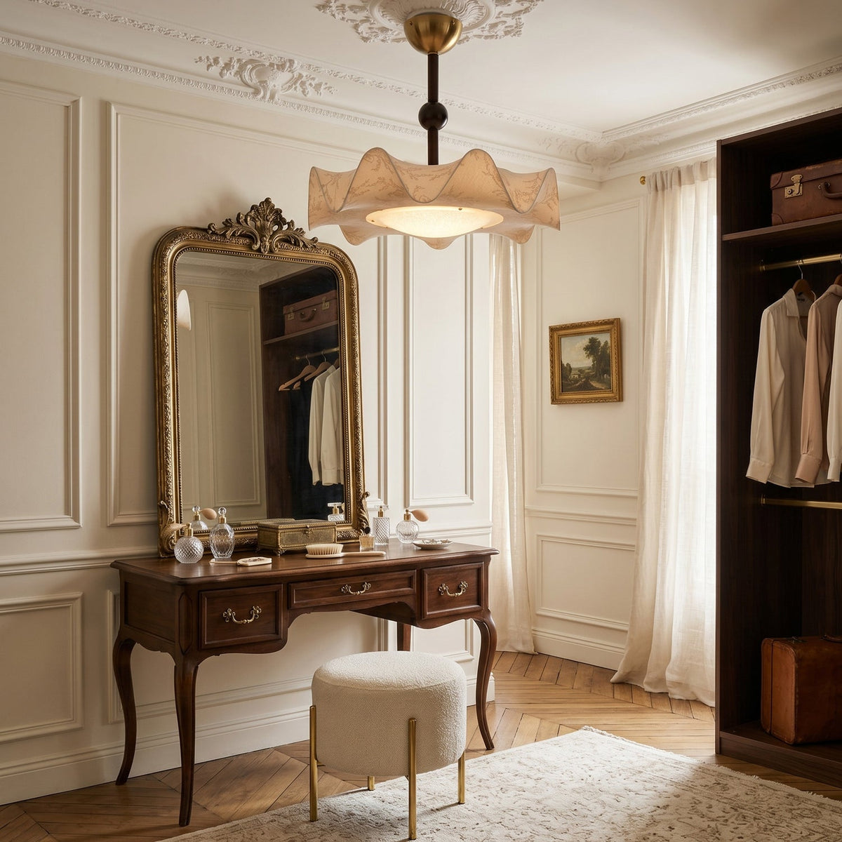 Clérachic ceiling light above a dressing room with a carved vanity table, a gilt mirror and a wardrobe of hanging shirts.