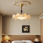 Clérachic ceiling light above a bed with a wooden headboard panel, with a small pendant and a wall light either side.