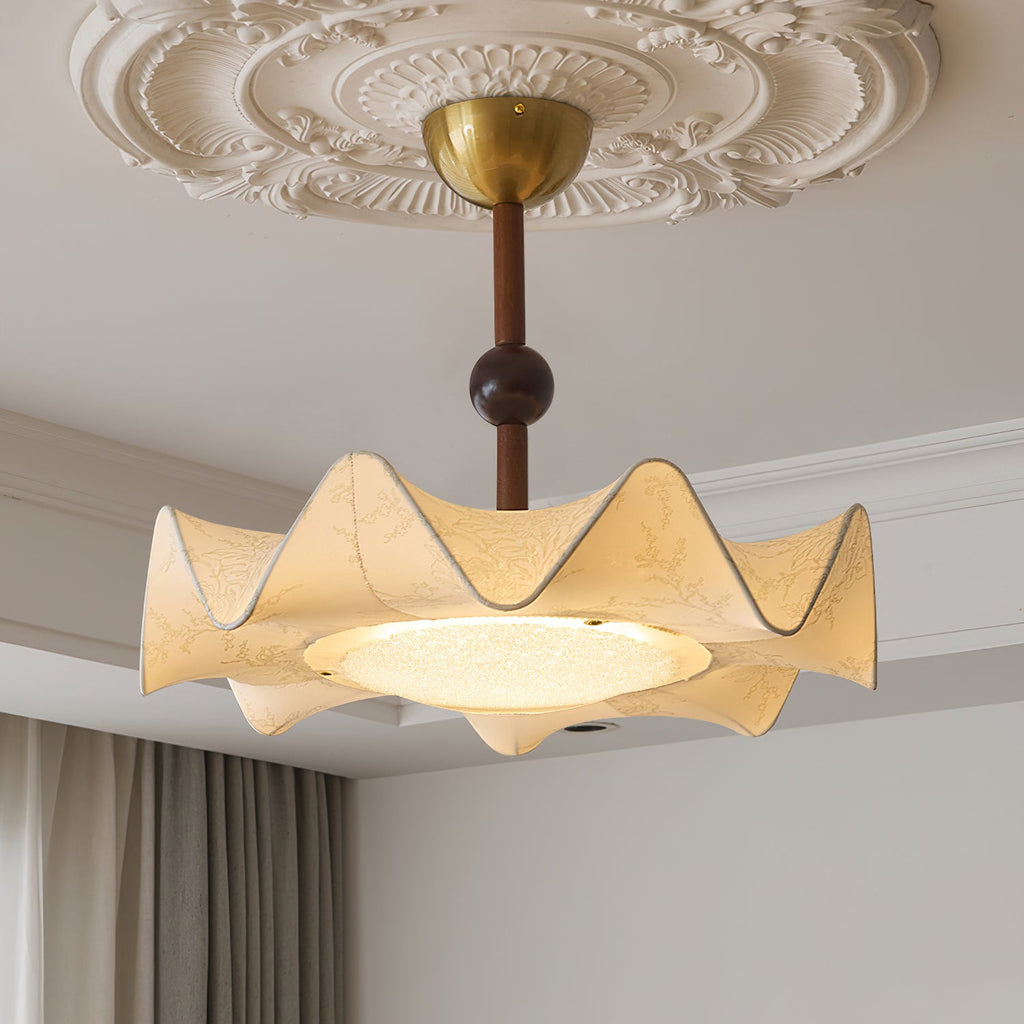 Close view of the lit diffuser and the scalloped cream shade of this Clérachic ceiling light under a decorated ceiling.