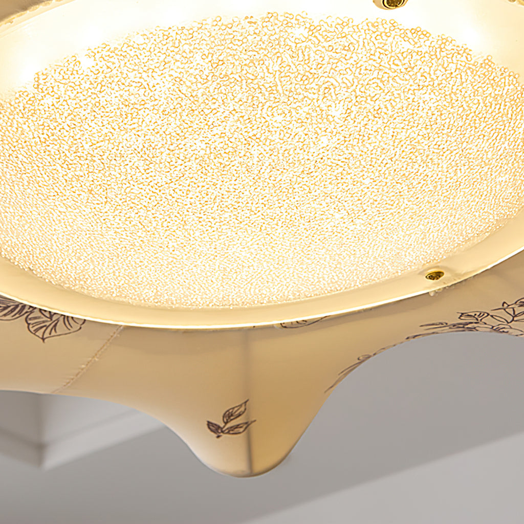 Close view of the frosted, speckled glass diffuser and the leaf print at the edge of this Clérachic ceiling light.