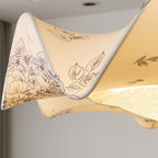 Underside view of this Clérachic ceiling light's folded fabric edge, printed with fine leaf and flower drawings, lit from within.