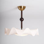 Side view of this Clérachic ceiling light, showing the stem with a dark ball, the pleated shade and the glow below.