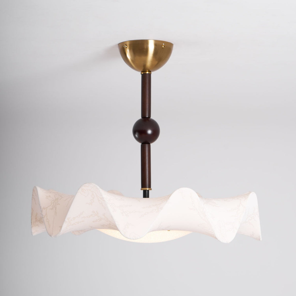Side view of this Clérachic ceiling light, showing the stem with a dark ball, the pleated shade and the glow below.