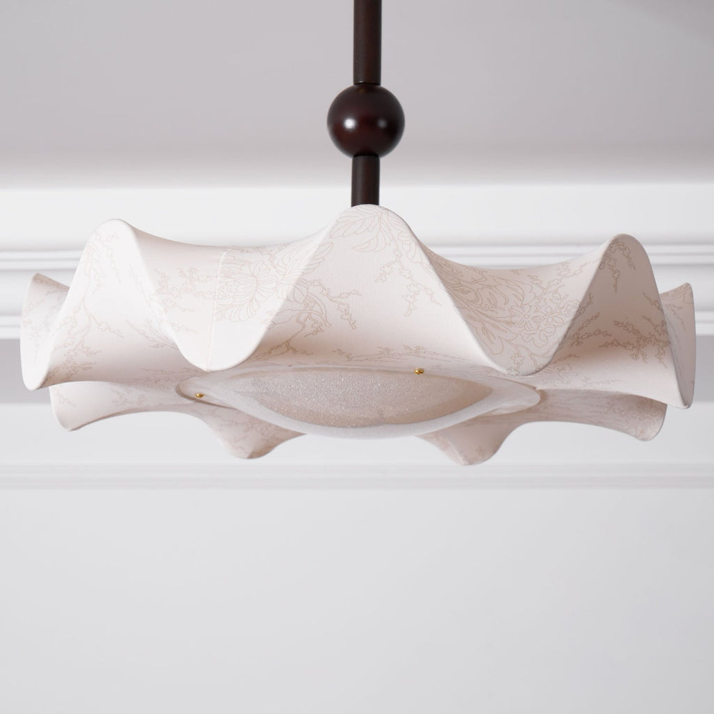 Wide view of the wavy shade on this Clérachic ceiling light, with the stem and dark ball above, under a white cornice.