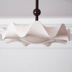 Wide view of the wavy shade on this Clérachic ceiling light, with the stem and dark ball above, under a white cornice.