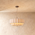 This Clérachic ceiling pendant hangs a two-tier scalloped fabric drum shade from a slim rod against plaster.