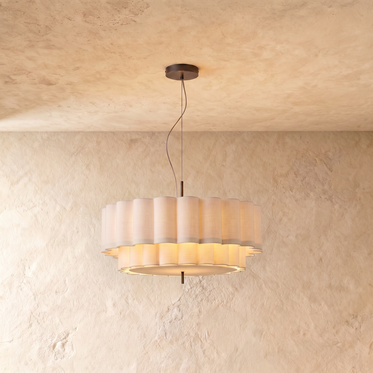 This Clérachic ceiling pendant hangs a two-tier scalloped fabric drum shade from a slim rod against plaster.